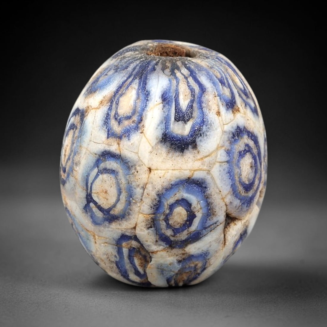Ancient Glass Bead - Roman Millefiori Eye Bead Pendant, 40BG: A spherical ancient glass bead crafted in the millefiori mosaic technique, with an opaque white glass base overlaid with intricate fused cane patterns. The surface is decorated with repeating concentr
