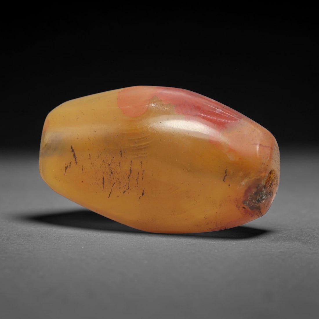 Ancient Agate Bead - Indus Valley Carnelian Barrel Bead, 9XW: This bead is carved from translucent honey-yellow carnelian agate with striking warm red-orange mineral inclusions, shaped into a refined faceted barrel form with a precisely centered axial drill hole