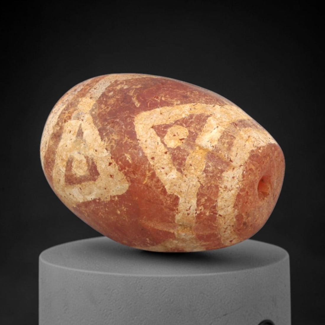 Ancient Carnelian Etched Bead - Gandhara Amulet, 51XY: Carved from carnelian, the bead is fashioned in an oval barrel form with a lateral drilled suspension hole for wear. The surface is decorated with a bold white-etched geometric pattern of nested trian