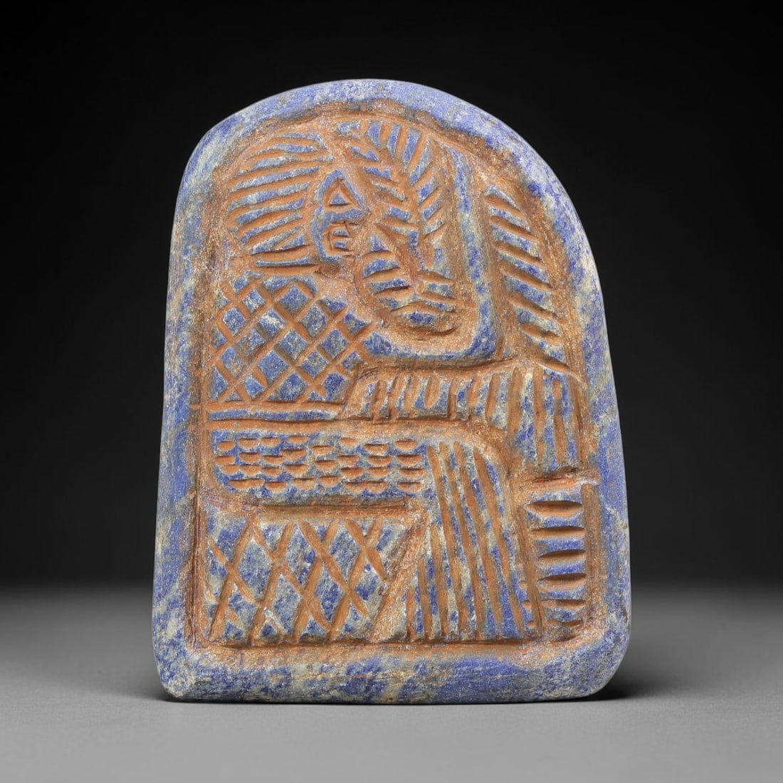 Near Eastern Lapis Lazuli Plaque - Tribal Art Relief Figure, 100BF: Carved from lapis lazuli, this rounded rectangular plaque features a relief depiction of a stylized anthropomorphic figure, rendered with incised linear and geometric detailing characteristic of Near