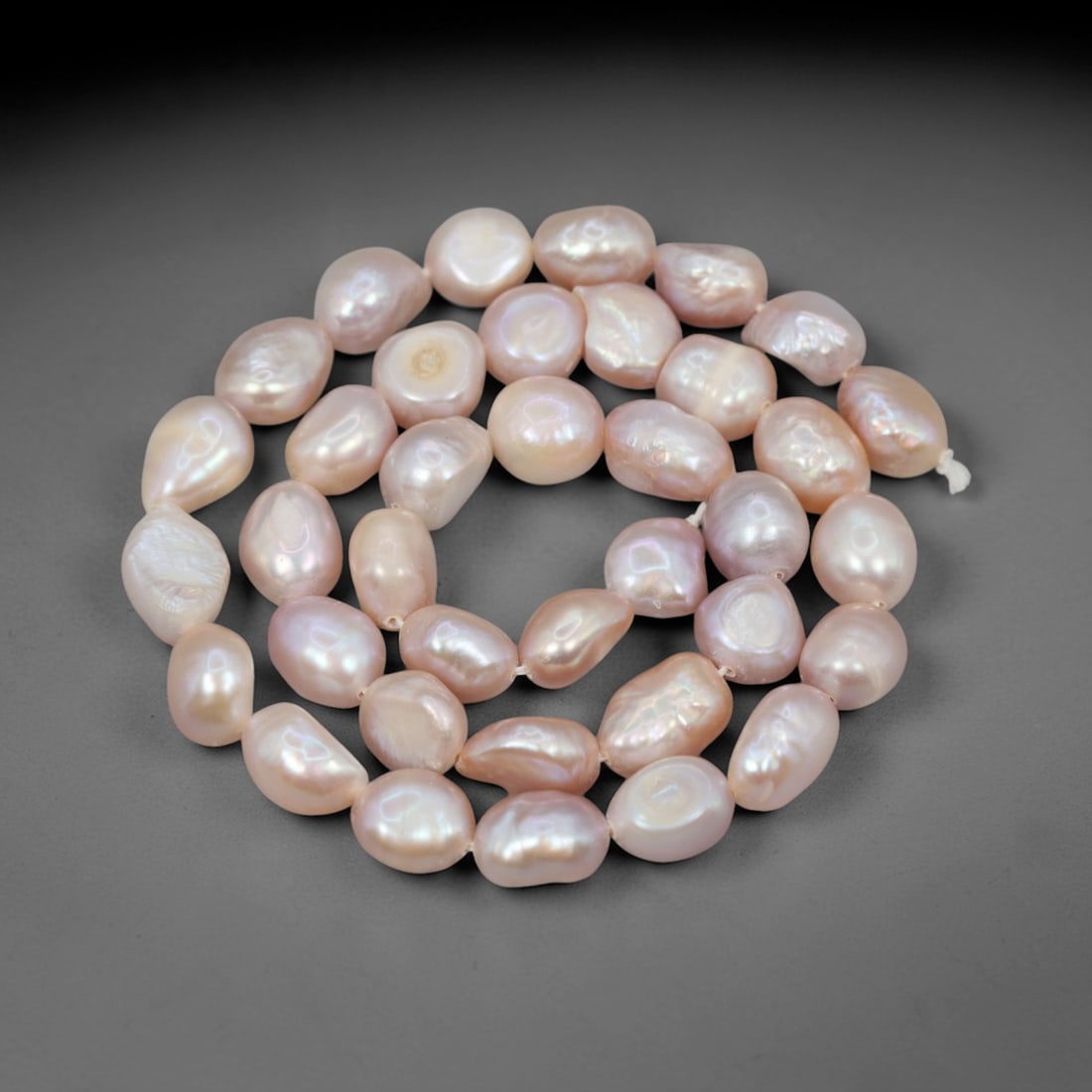 A Strand of Baroque Cultured Pearls, 20th Century, 79ZJ: Composed of baroque cultured pearls with a uniform pale pink body color and subtle iridescent overtones, the strand is strung in a single continuous line. Each pearl exhibits a characteristic irregula
