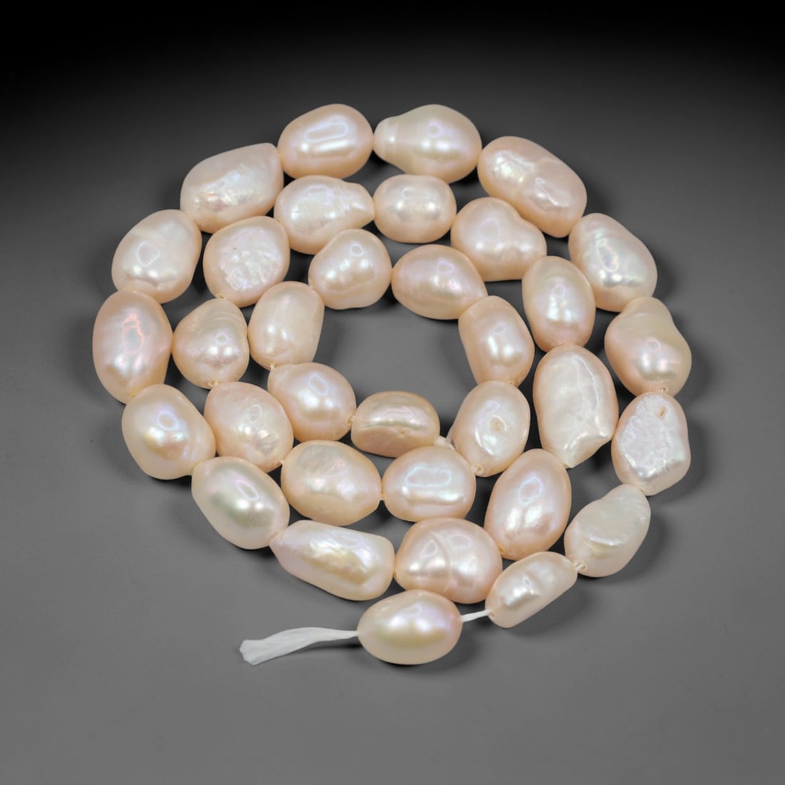 A Strand of Baroque Cultured Pearls, 20th Century, 80ZJ: Composed of baroque cultured pearls with a pale creamy-white body color and soft iridescent overtones, the strand is strung in a single continuous line. Each pearl exhibits an irregular, non-symmetric