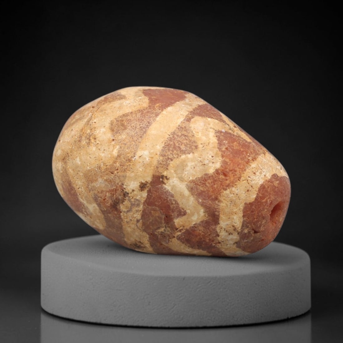 Ancient Carnelian Etched Bead - Gandhara Amulet, 55XY: Carved from carnelian, the bead is fashioned in an elongated teardrop form with a lateral drilled suspension hole for wear. The surface is decorated with a bold white-etched pattern of curvilinear ban