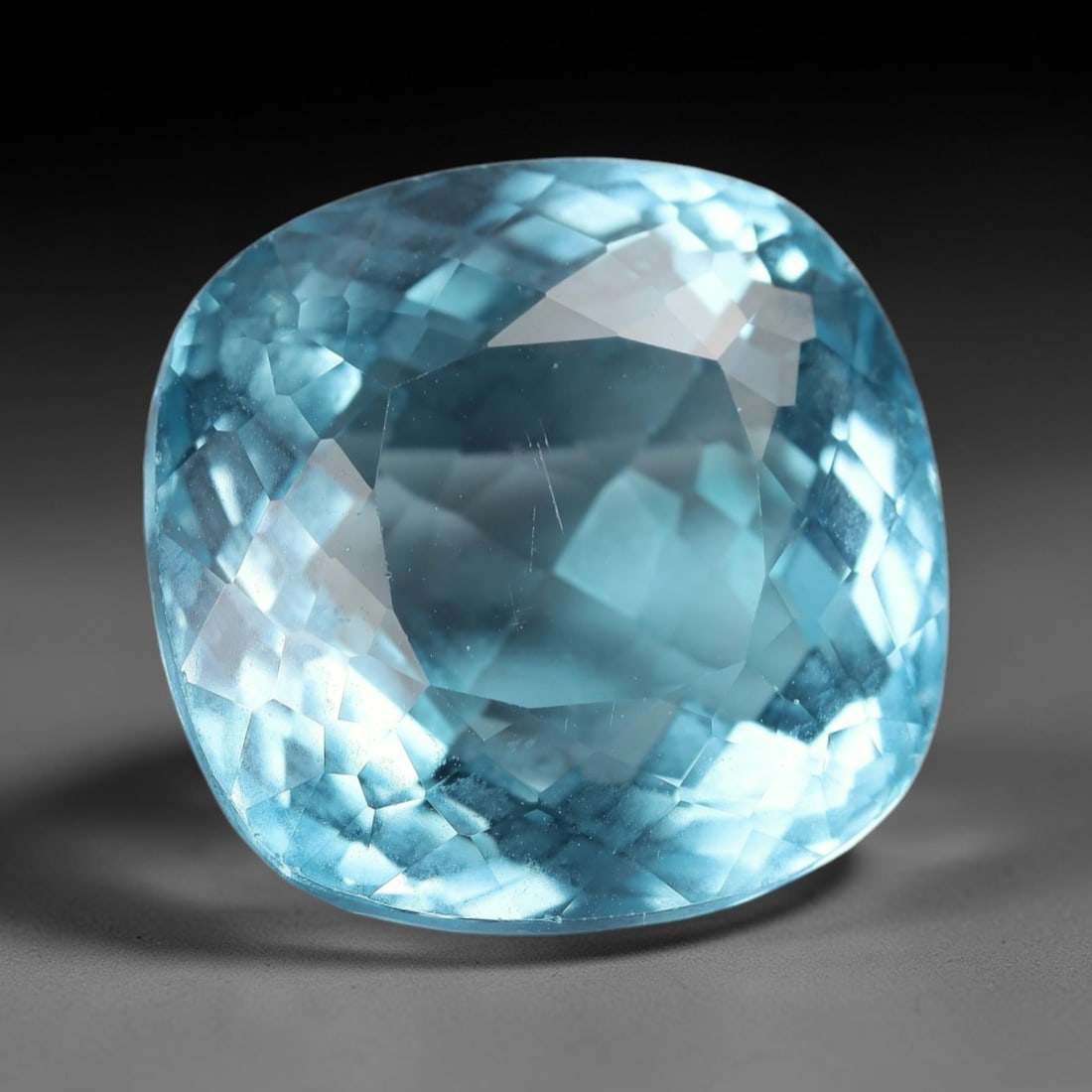 26.941 Carats Certified Bright Blue Topaz - Natural Brazilian Gemstone, LZ282: This extraordinary 26.941 carat cushion fancy-cut topaz is a true showstopper, boasting a vivid, saturated bright blue hue that evokes the clarity of a tropical ocean and the brilliance of a cloudless