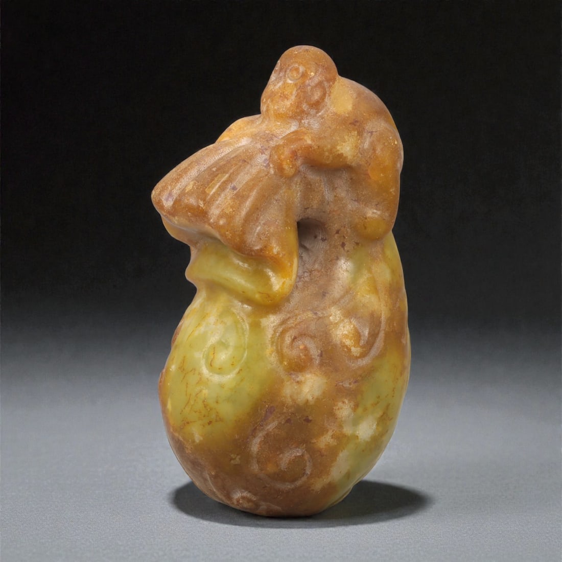A Chinese Jade Monkey and Peach Carving, 20th Century, 80YA: Carved from translucent jade with warm honey-brown and yellow tonal variation, the sculpture is worked fully in the round as a vertical composition. The form depicts a monkey perched atop a large peac