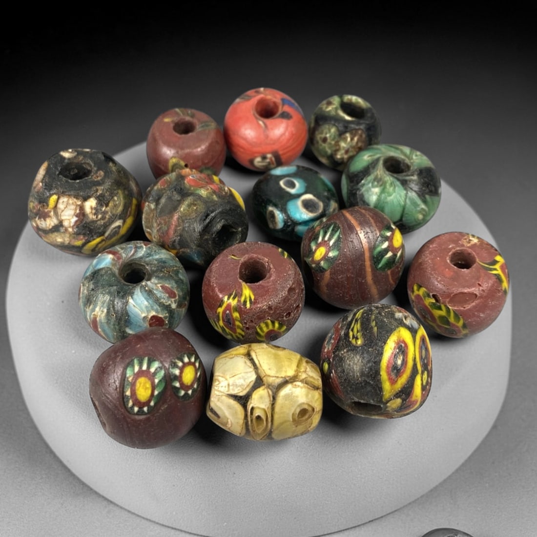 Antique Venetian Glass Beads - 14 Pieces, 16ZT: This set of 14 antique Venetian glass beads features hand-formed spherical shapes, crafted from polychrome glass with intricate mosaic and cane-work patterns characteristic of traditional Venetian gla