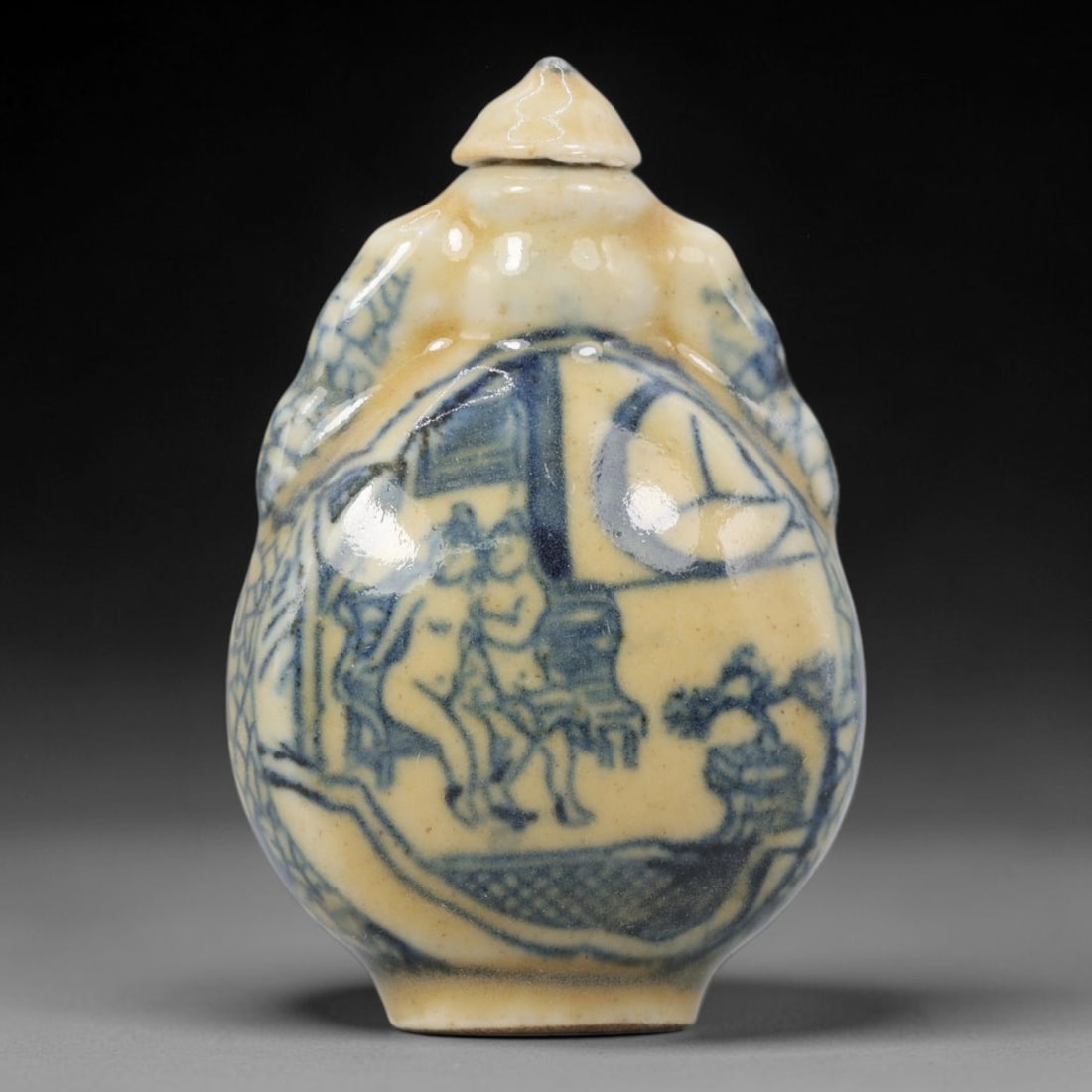 A Chinese Porcelain Snuff Bottle, 20th Century, 8YD: Crafted from porcelain with a pale cream glaze and decorated in underglaze blue, the snuff bottle features a rounded body with molded figural handles to either side, a short cylindrical neck, and a co