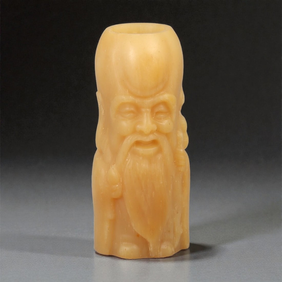 A Chinese Bone Carved Figural Vessel, 20th Century, 26YB: Carved from pale honey-toned bone with natural translucency and fine longitudinal striations, the object is formed as a hollow vessel with an open mouth and an uncovered base. The interior cavity foll