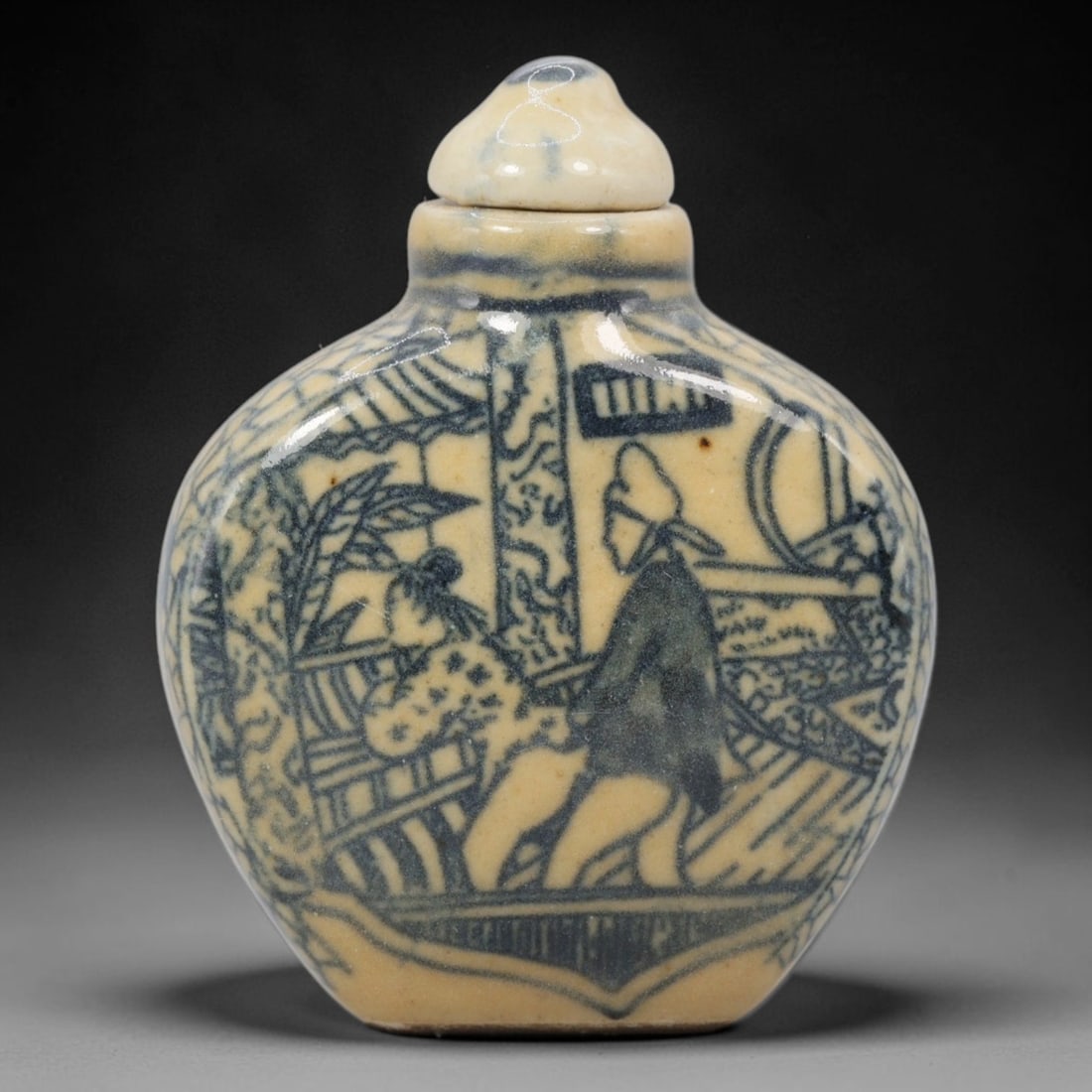 A Chinese Porcelain Snuff Bottle, 20th Century, 2YD: Made of porcelain with a pale yellowish glaze and underglaze blue decoration, the snuff bottle has a flattened, rounded body, a short cylindrical neck, and a matching domed stopper. The main surface i