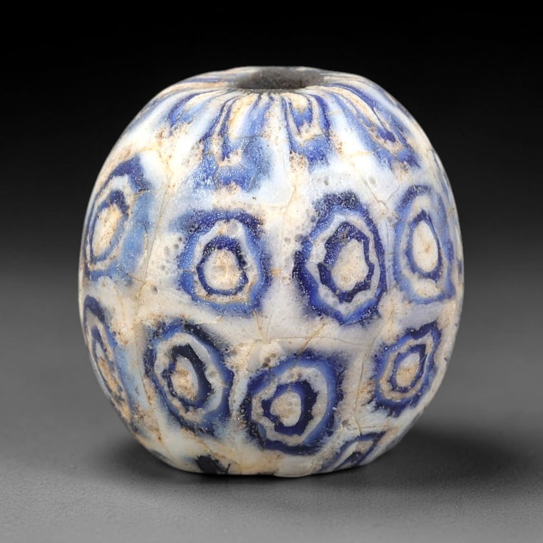 Ancient Glass Bead - Roman Millefiori Eye Bead Pendant, 32BG: A spherical ancient glass bead crafted in the millefiori mosaic technique, with an opaque white glass base overlaid with intricate fused cane patterns. The surface is decorated with repeating concentr