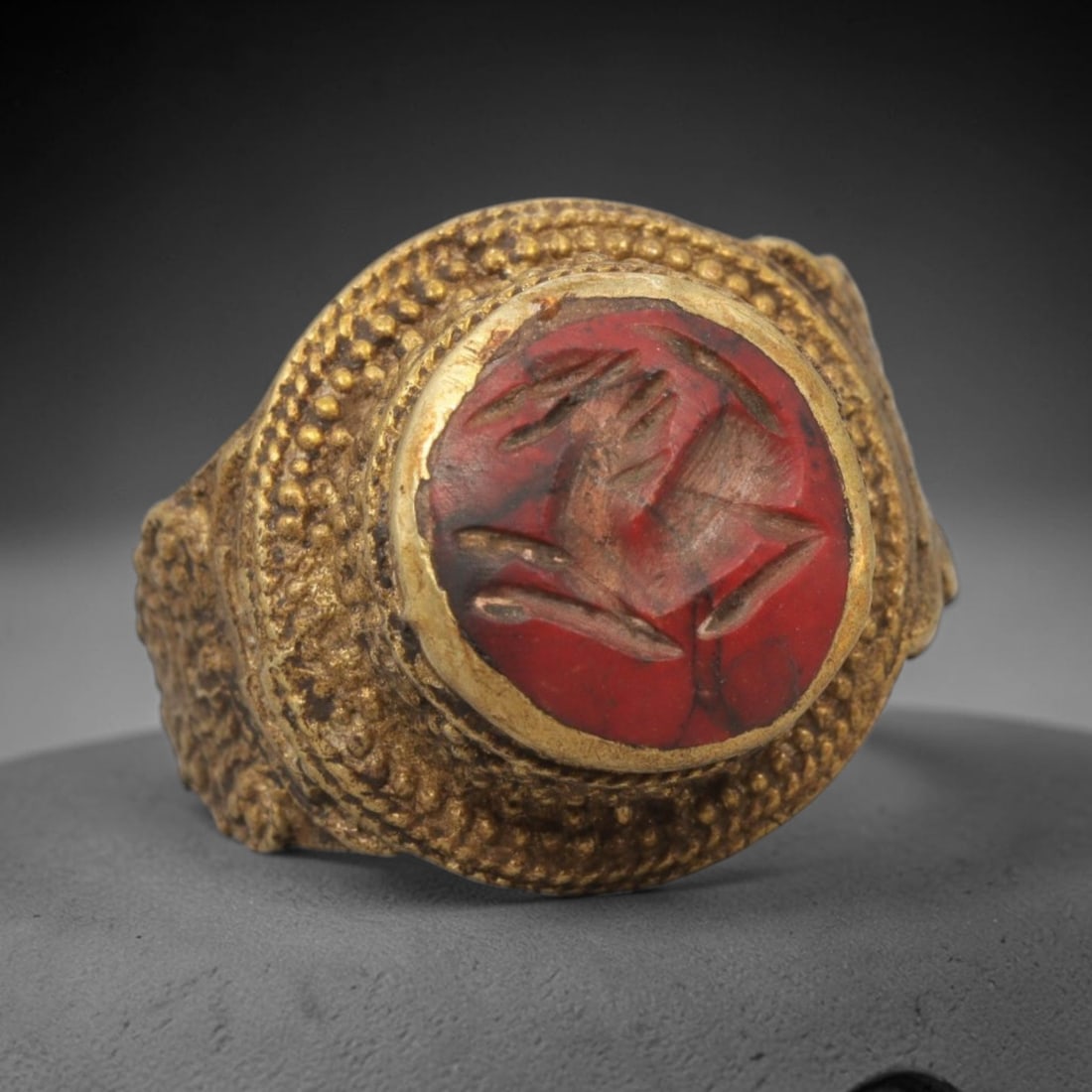 Antique Qajar Dynasty Red Stone Intaglio Ring - Size 7 US, 12WJ: Crafted from brass with an ornate domed bezel, this ring features a carved red stone intaglio at its center, incised with a stylized symbolic motif characteristic of Qajar-era Persian amuletic carving