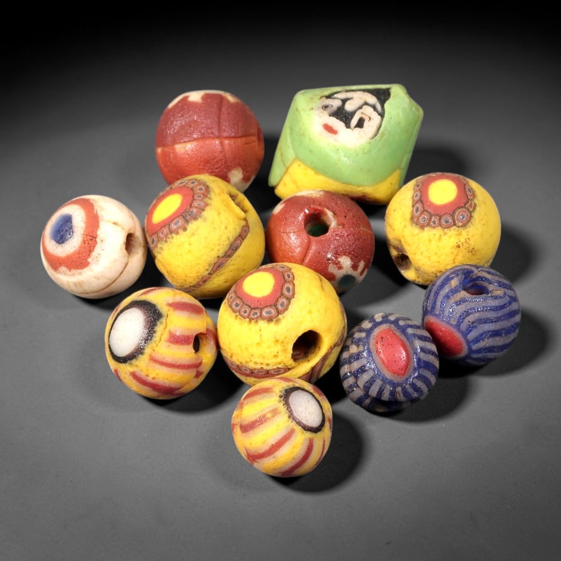 Old Glass Mosaic Eye Beads - Phoenician Style Mixed Beads, 92BG: Set of eleven old glass mosaic and eye beads, crafted from fused colored glass with a diverse array of decorative motifs across the collection. The set includes spherical and faceted beads, featuring 