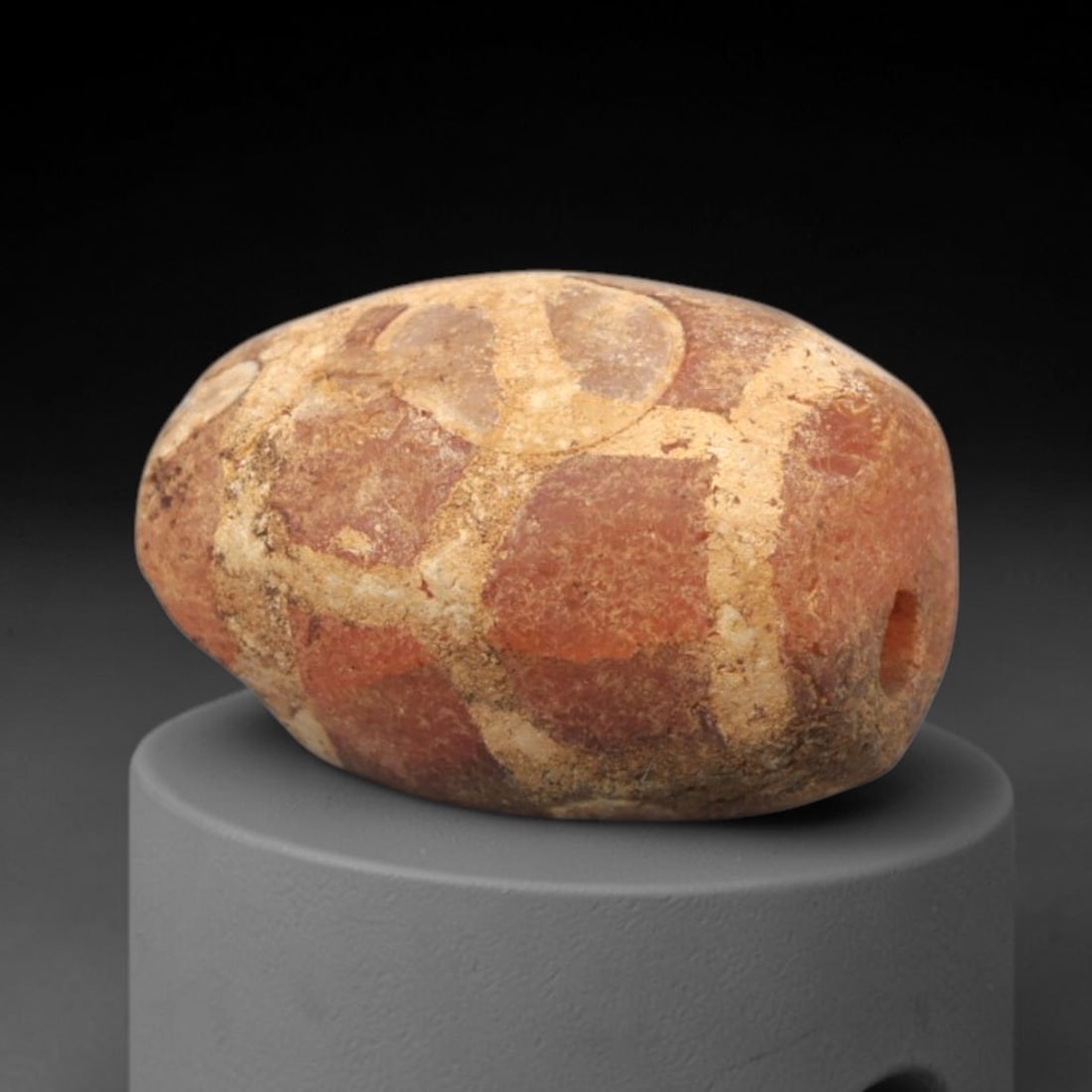 Ancient Carnelian Etched Bead - Gandhara Amulet, 40XY: Carved from carnelian, the bead is fashioned in an oval barrel form with a lateral drilled suspension hole for wear. The surface is decorated with a white-etched geometric pattern of interlocking squa