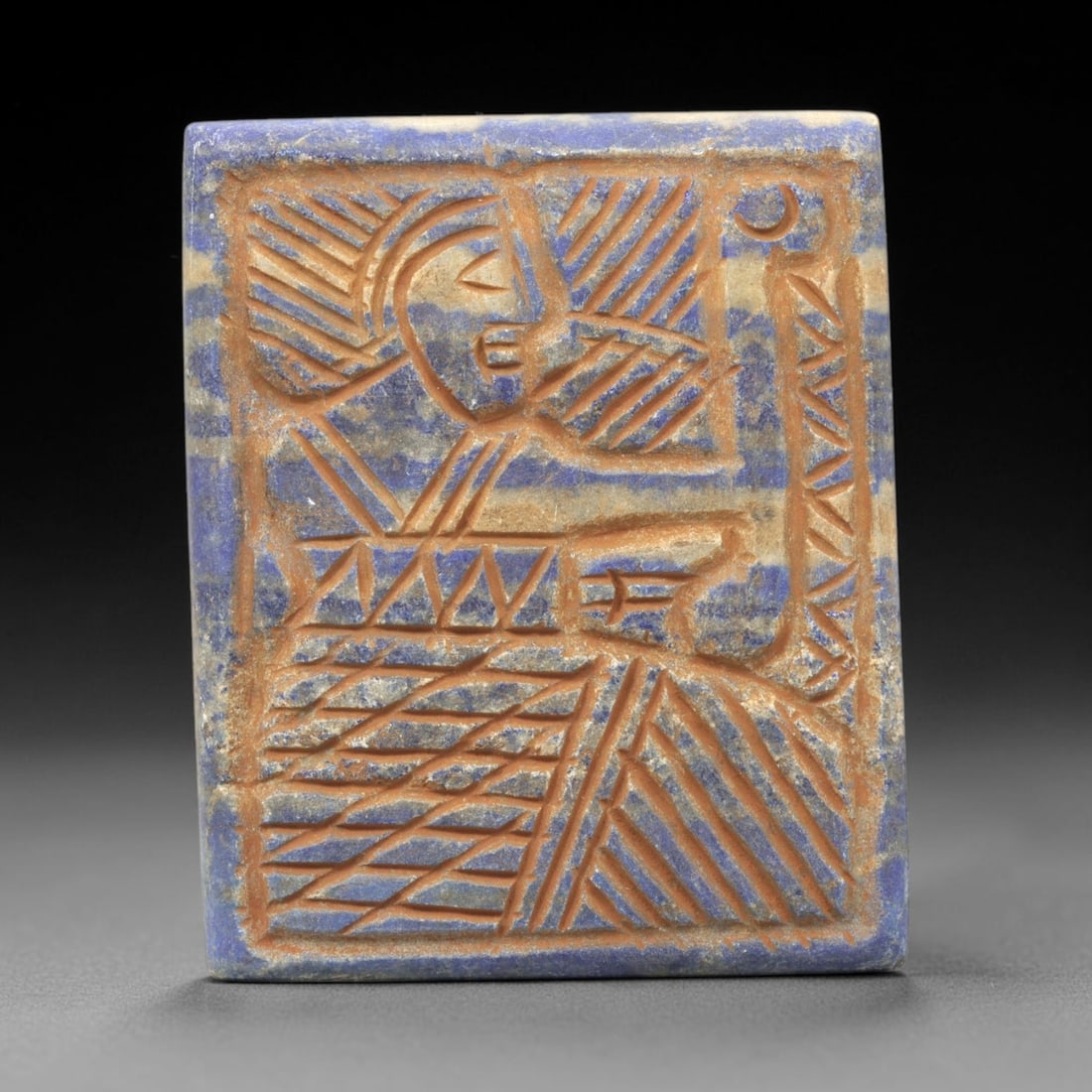 Near Eastern Lapis Lazuli Plaque - Tribal Art Figure & Moon Relief, 54ZY: Carved from lapis lazuli, this square plaque features a deeply incised relief depiction of a stylized human figure, rendered in a geometric Near Eastern tribal idiom. The figure is defined by intricat