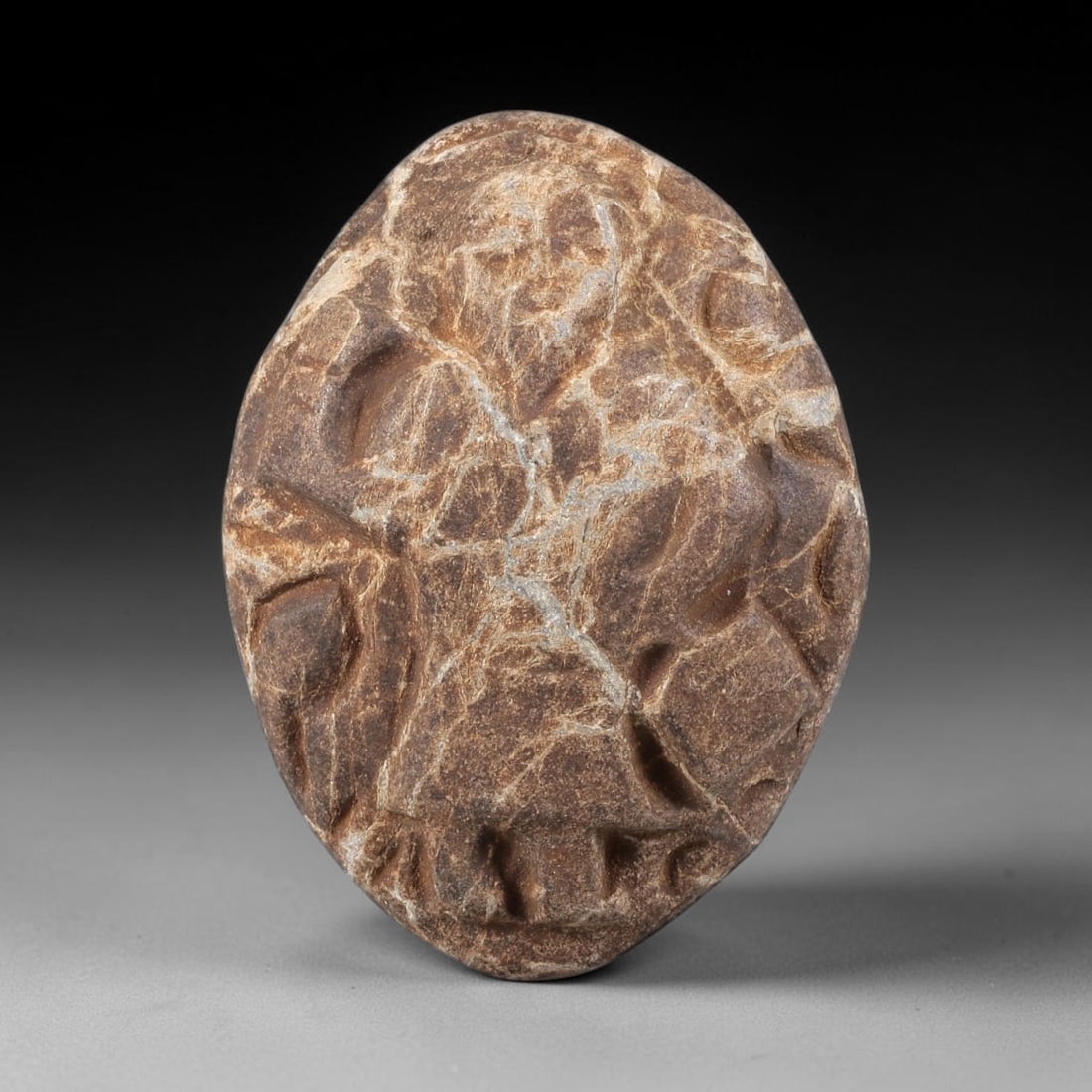Ancient Stone Figural Amulet - Christian Religious Relic, 70ZT: Carved from a textured, brown-hued stone with prominent grey veining, this figural amulet features a deeply incised relief depiction of a sacred Christian figural form, likely a saint or biblical figu