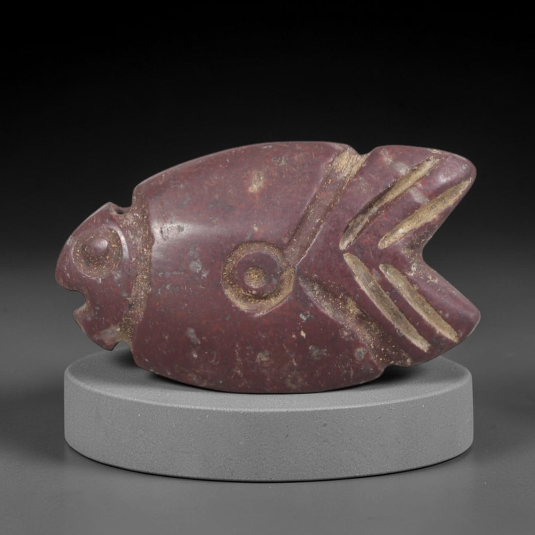 Ancient Stone Fish - Near Eastern Amulet Figurine, 35AP: This artifact is carved from deep red stone with a weathered, earthy patina and subtle mineral inclusions, exhibiting stylized piscine features consistent with ancient Near Eastern stoneworking techni