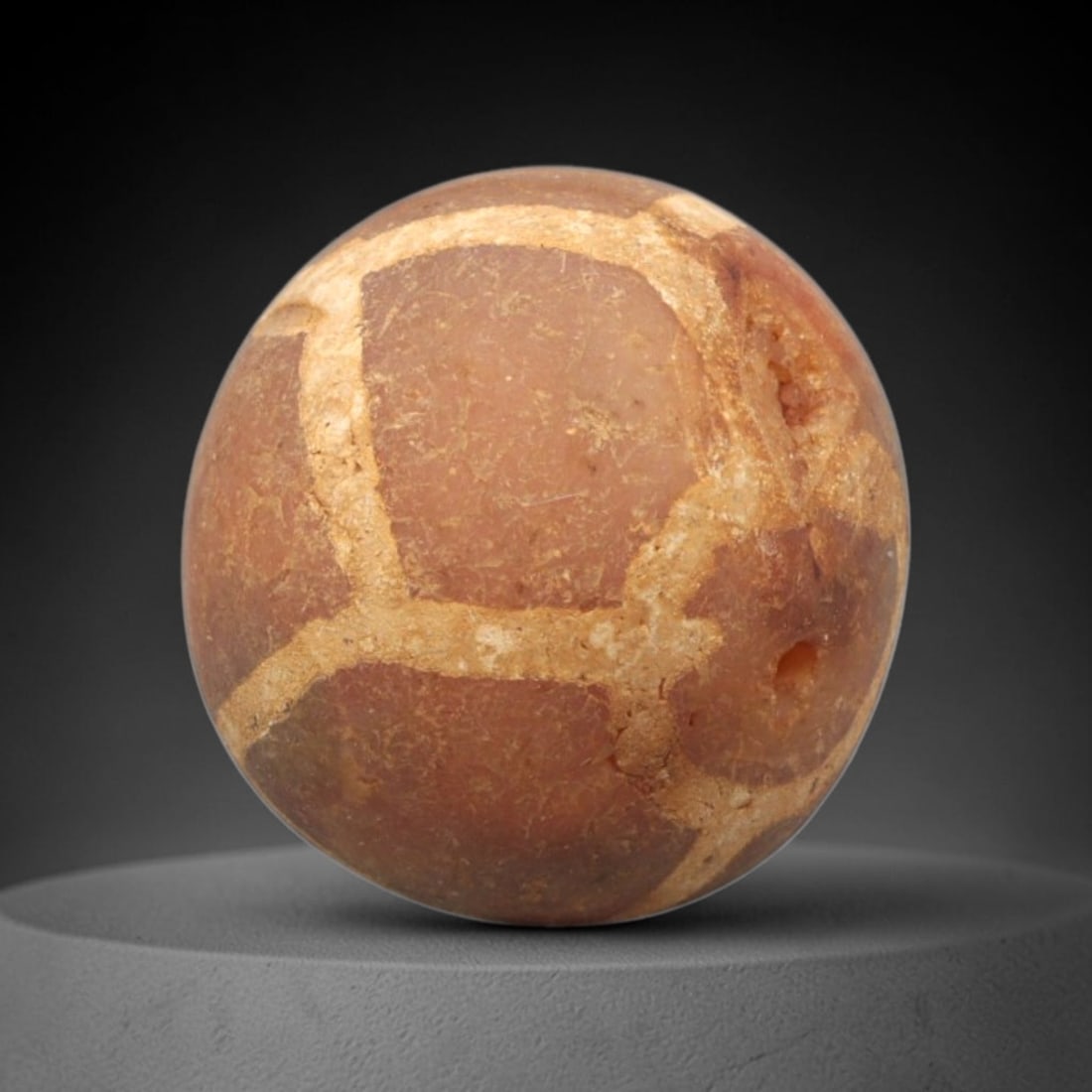 Ancient Carnelian Etched Bead - Gandhara Spherical Bead, 29XY: The bead is carved from carnelian, a semi-precious chalcedony, with a spherical form and a laterally drilled suspension hole. Its surface features an etched white geometric lattice pattern, created us