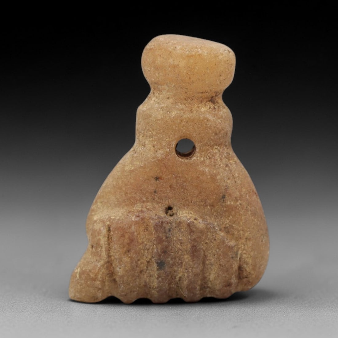 Ancient Stone Fist Amulet - Near Eastern Figurine, 56ZW: This amulet is carved from light tan stone, shaped into a stylized closed fist, a motif associated with protection and power in ancient Near Eastern iconography. A suspension hole pierces the upper se