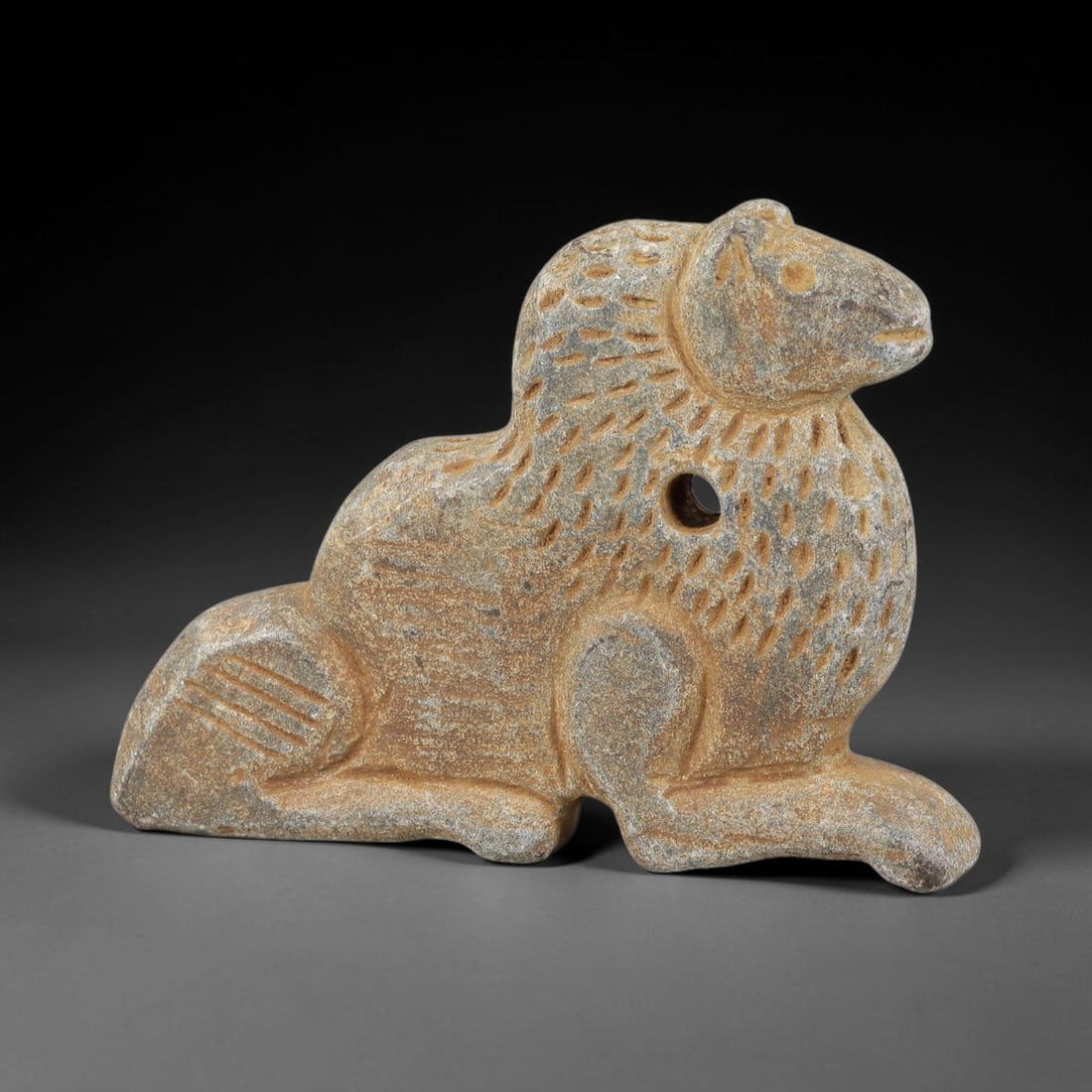 Ancient Schist Recumbent Lion Amulet - Near Eastern Carved Figurine, 57BA: Carved from schist, this amulet takes the form of a stylized recumbent lion (a powerful protective symbol in ancient Near Eastern culture), rendered in three dimensions with detailed, stylized carving