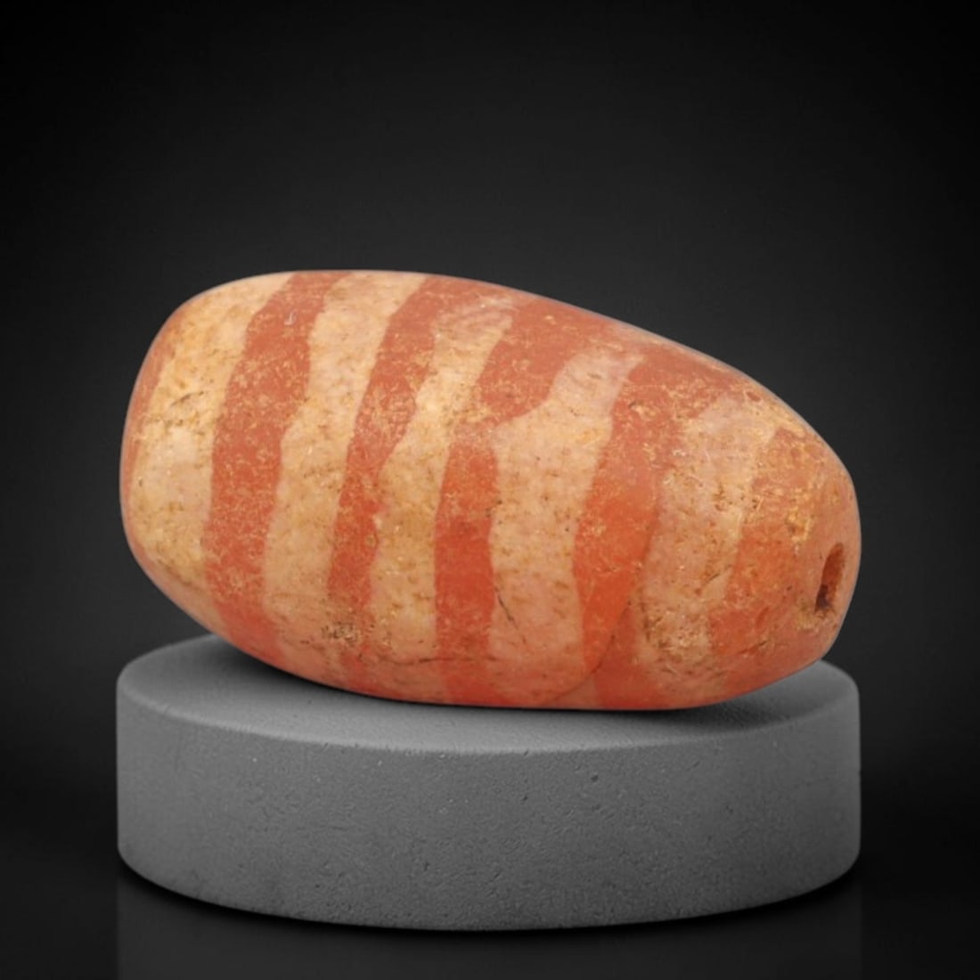 Ancient Carnelian Etched Bead - Gandhara Amulet, 49XY: Carved from carnelian, the bead is fashioned in an elongated barrel form with a lateral drilled suspension hole for wear. The surface is decorated with bold, alternating red and white-etched vertical