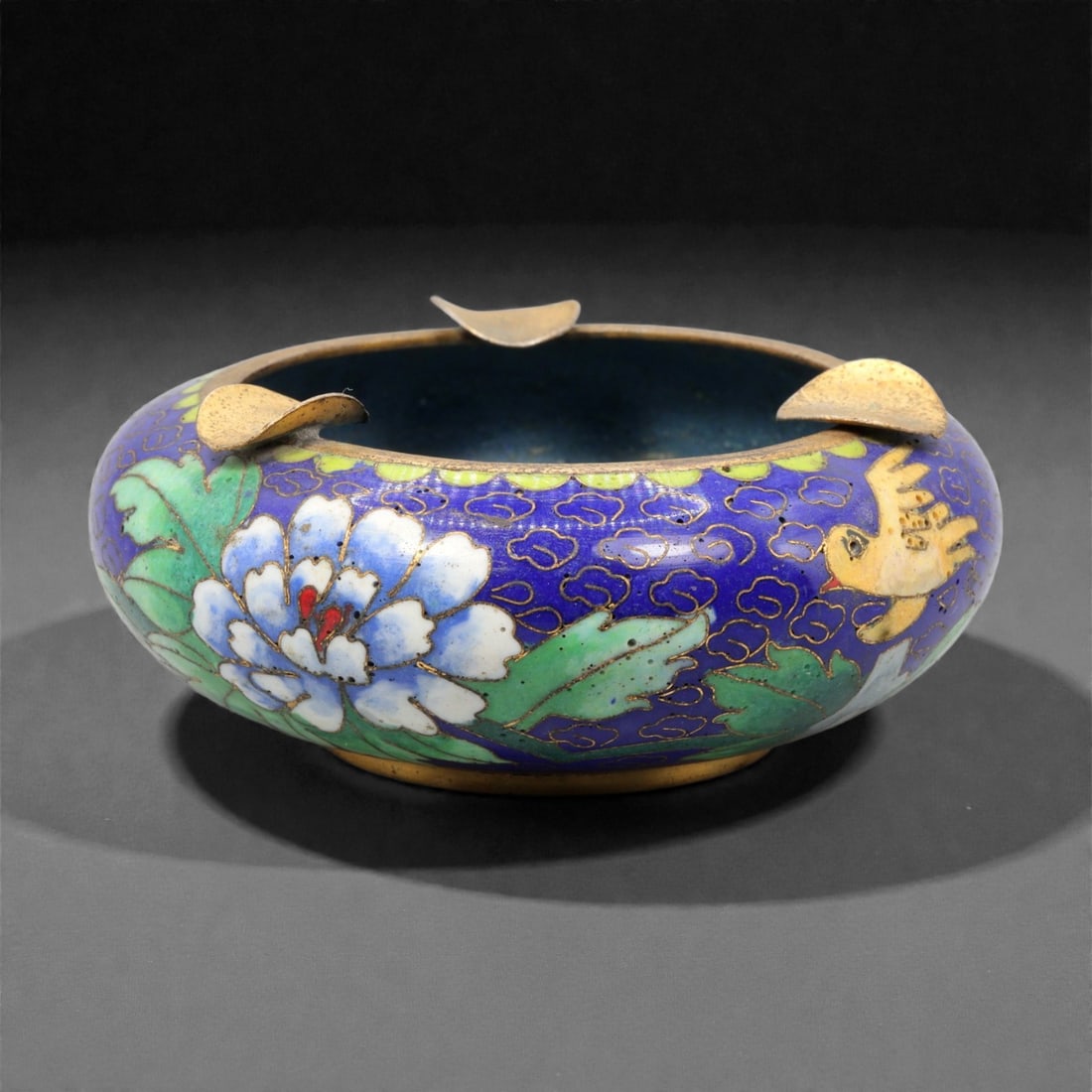 A Chinese Cloisonne Enamel Ashtray, 20th Century, 88YC: Constructed in copper and decorated with polychrome cloisonne enamel, the ashtray is formed with a shallow circular body and a slightly recessed interior, supported on a narrow foot ring. The rim is f