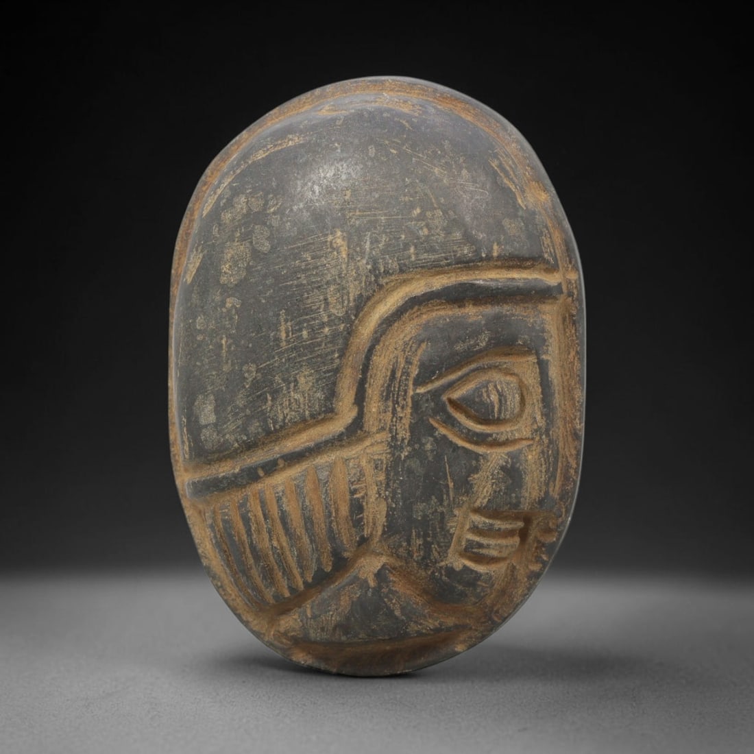 Ancient Stone Amulet - Near Eastern Bust Plaque Pendant, 22ZX: Carved from stone, the amulet is an oval plaque crafted in the ancient Near Eastern style, featuring a raised relief portrait of a human bust in profile. The surface bears incised details rendering a