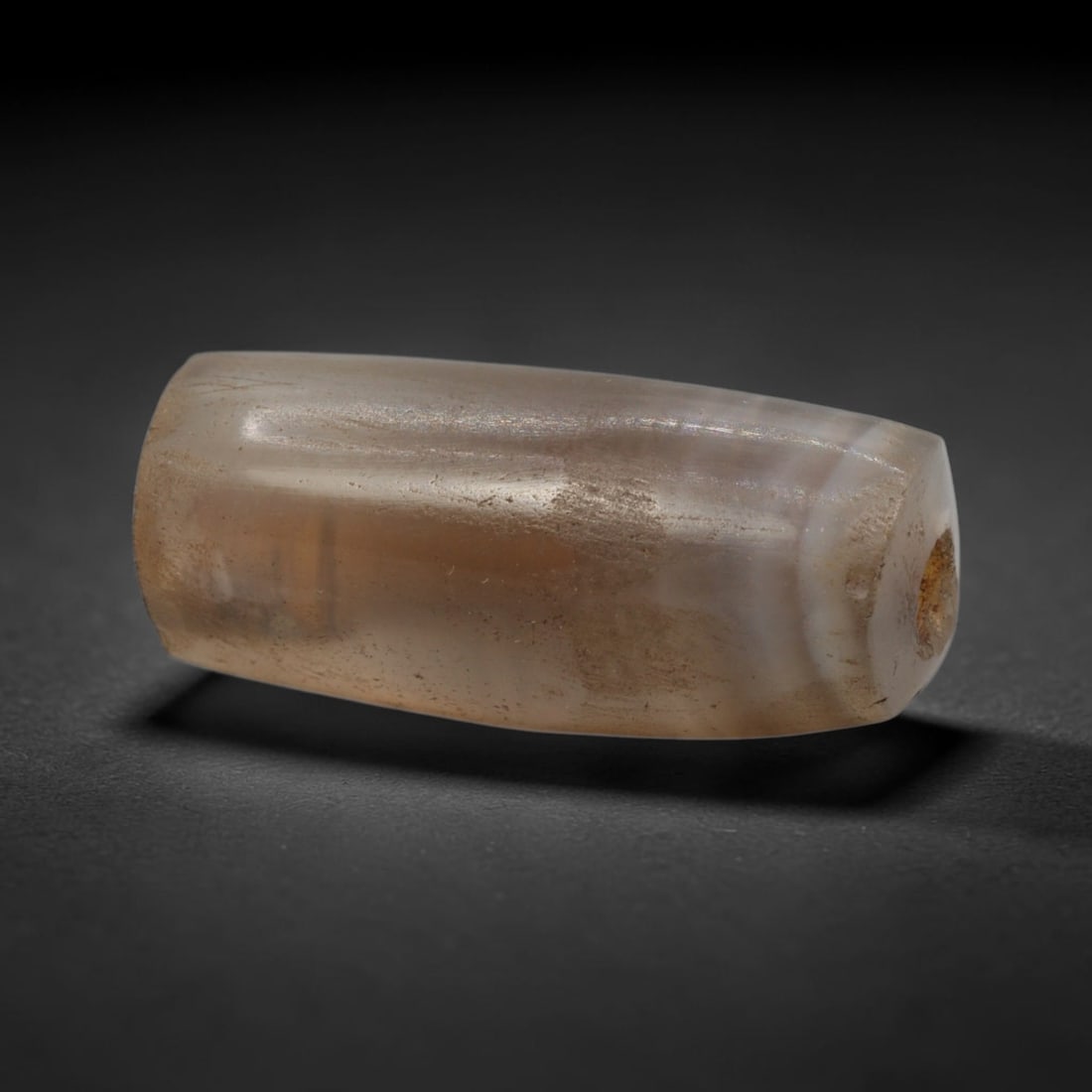Ancient Agate Bead - Western Asiatic Cylindrical Bead, 66XW: This bead is fashioned from translucent milky-grey banded agate, shaped into a smooth, uniform cylindrical form with a precisely centered axial drill hole, characteristic of Western Asiatic lapidary t