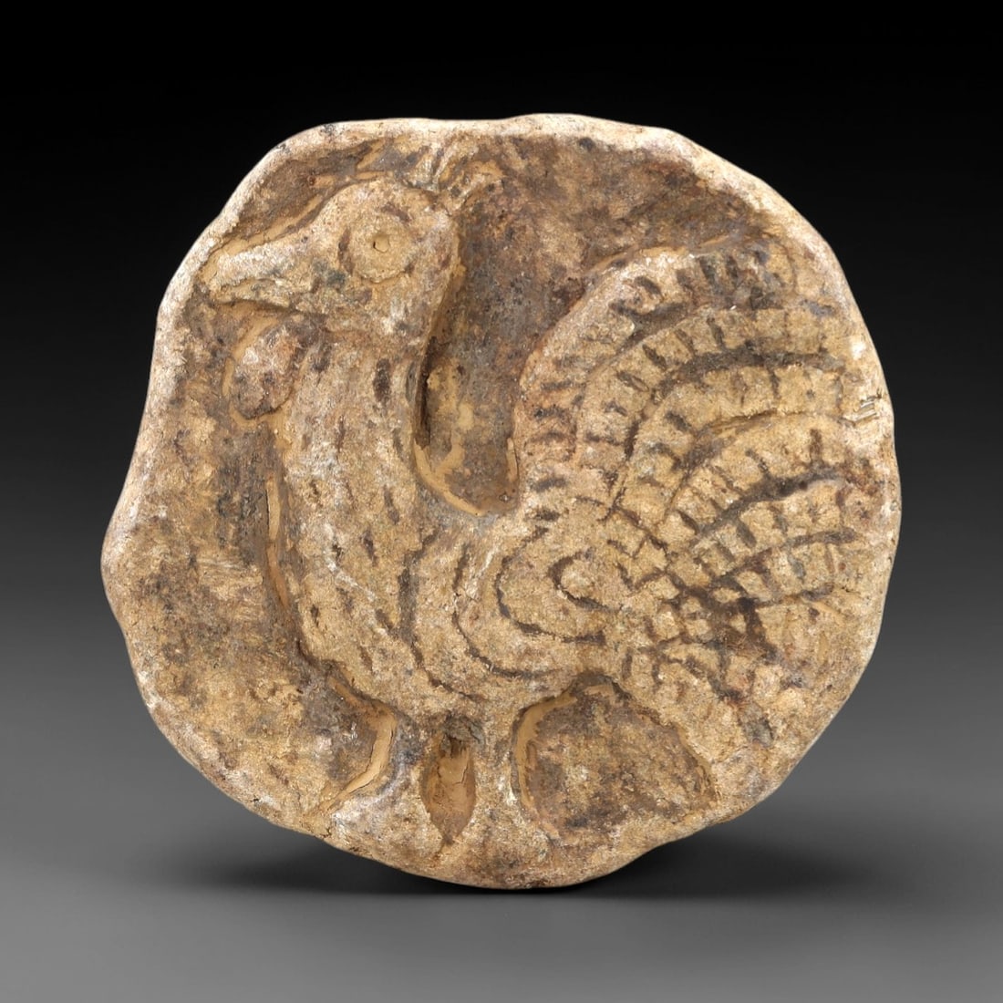 Ancient Stone Relief Plaque - Near Eastern Bird Figure, 79AL: This artifact is carved from stone, formed into a circular relief plaque with a raised depiction of a stylized bird, likely a rooster or avian amuletic figure, featuring detailed incised feather patte