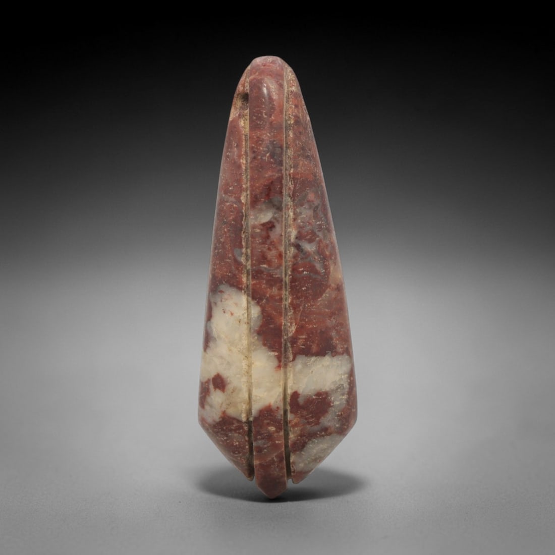 Ancient Near Eastern Red & White Brecciated Jasper Teardrop Amulet - Carved Pendant Figure, 47ZV: This amulet is carved from a striking variegated red-and-white brecciated jasper, featuring an elegant teardrop form. The piece is defined by two parallel vertical grooves running its entire length, c