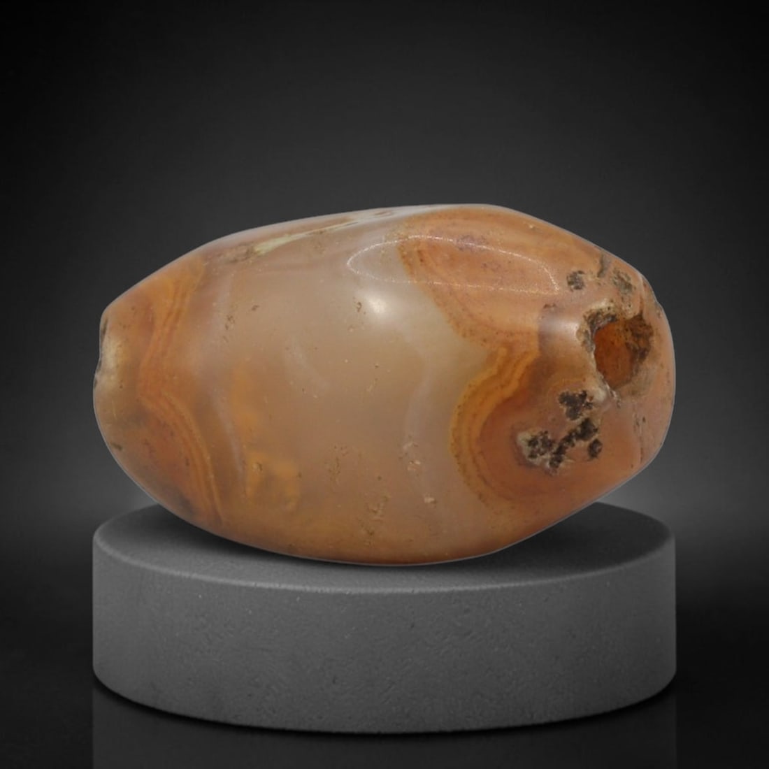 Ancient Agate Bead - Bactrian Banded Barrel Bead, 18XW: This bead is carved from translucent honey-amber and warm orange banded agate, shaped into a smooth, compact barrel form with a precisely centered axial drill hole, characteristic of ancient Bactrian