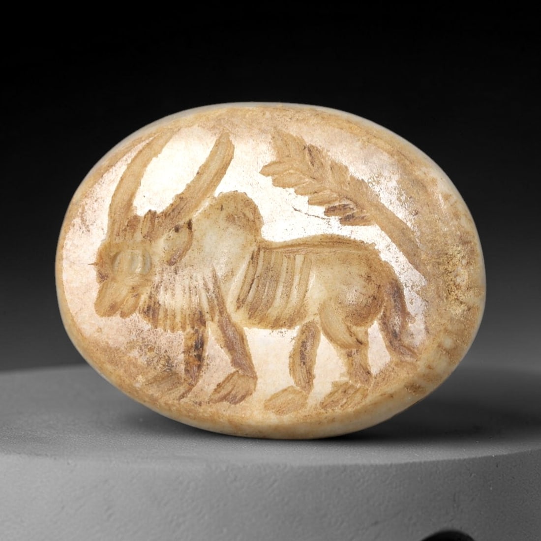 Ancient Stone Bull Intaglio - Near Eastern Amulet, 41AR: This oval intaglio is carved from a pale, creamy stone matrix, featuring a high-relief depiction of a bull in striding pose, with prominent curved horns and incised linear details defining its ribcage