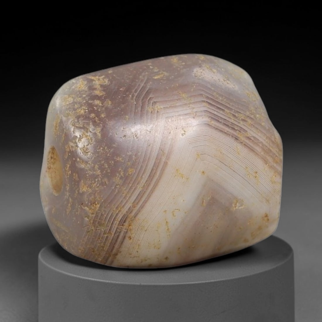 Ancient Agate Bead - Silk Road Miniature Amulet, 76BC: Carved from banded agate, the bead features a smooth, rounded barrel form with a polished surface that highlights the stone's striking "chevron" (V-shaped) concentric banding, ranging from smoky gray