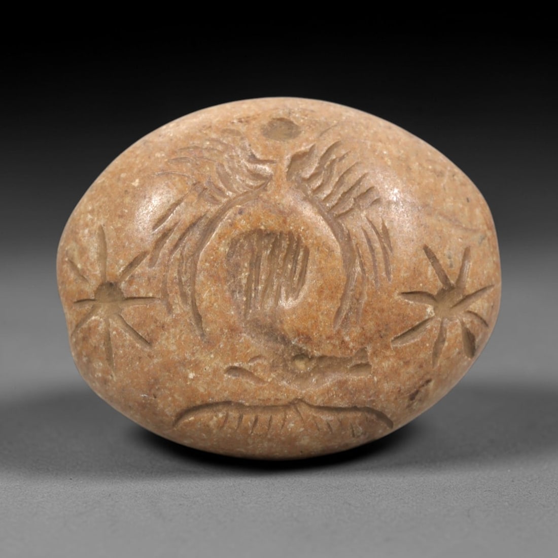 Ancient Stone Intaglio Bead - Greco-Bactrian / Near Eastern Cosmic Motif Artifact, 11ZR: This artifact is an oval stone intaglio bead, executed in the decorative tradition of the ancient Greco-Bactrian or Near Eastern world. The face features a central winged or vegetal motif flanked by s