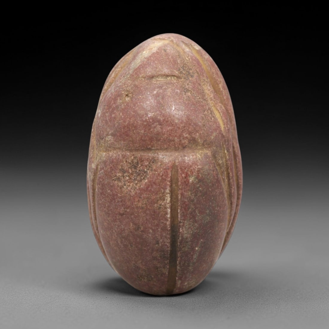 Ancient Egyptian Red Stone Scarab - Amulet Figurine, 54ZR: This artifact is a carved red stone scarab amulet, crafted from a granular, reddish-brown stone with a smooth, worn surface and natural earthy patina concentrated in the incised linear details. The do