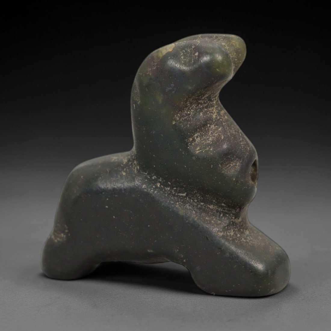 Ancient Green Stone Zoomorphic Amulet - Near Eastern Figurine, 14AE: Carved from deep green stone with natural mineral speckling, this amulet takes a stylized zoomorphic form, rendered in a compact, abstract posture with simplified, rounded contours. The piece features