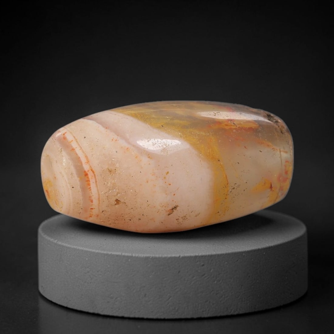 Ancient Agate Bead - Silk Road Amulet, 71BD: This artifact is crafted from variegated agate, showcasing soft bands of pale pink, warm amber, and creamy white with subtle red mineral inclusions, shaped into a smooth barrel form through skilled an