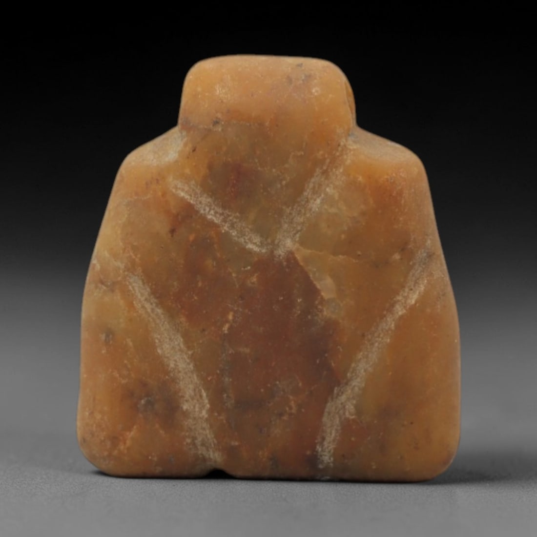Ancient Stone Eye Idol - Near Eastern Ritual Figurine, 57XR: Carved from warm orange-brown stone, this miniature idol features a stylized trapezoidal form with a raised upper section and incised linear markings evoking eye motifs, consistent with Ancient Near E