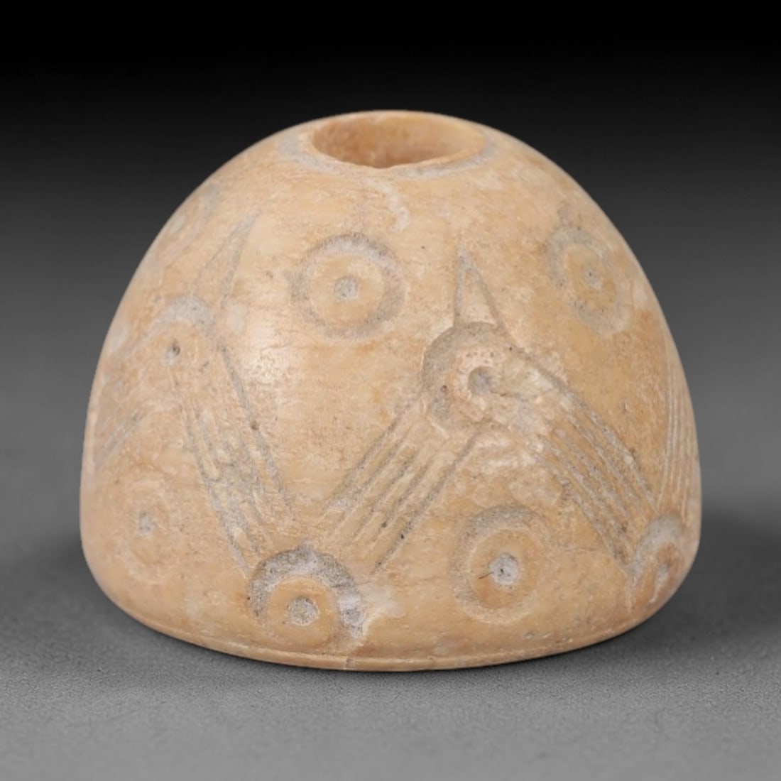 Ancient Near Eastern Bone Spindle Whorl - Dot-in-Circle Motif, 97AH: Carved from ancient bone, this Near Eastern spindle whorl features a continuous dot-in-circle motif encircling its central perforation, a design with apotropaic significance in ancient Near Eastern cu