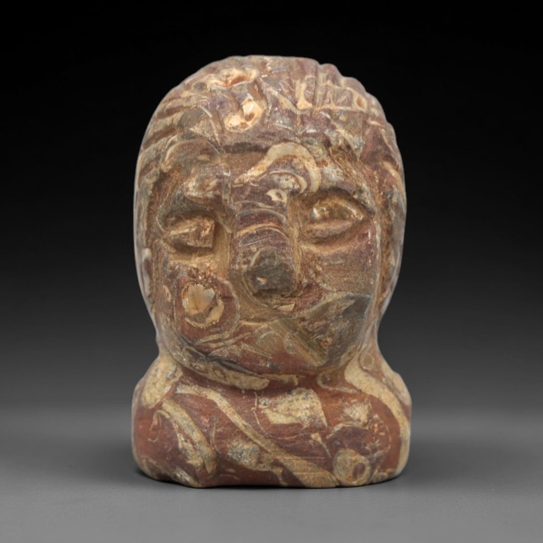 Ancient Stone Head Amulet - Mediterranean Anthropomorphic Figurine, 28ZR: This artifact is a carved stone head amulet, executed in the stylized anthropomorphic tradition of the ancient Mediterranean or Near East. The amulet depicts a compact human head with incised facial f