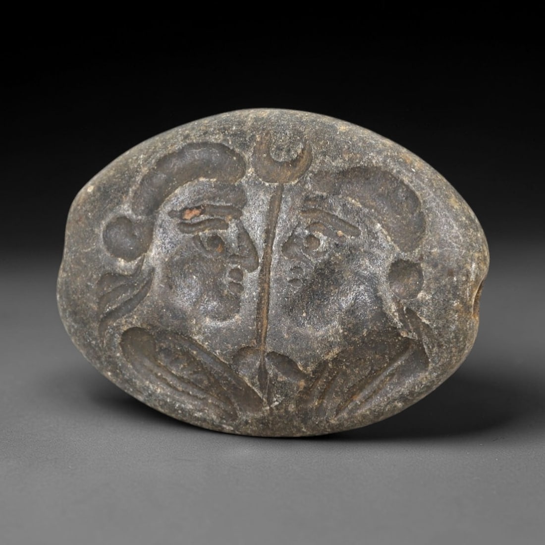 Ancient Stone Intaglio Bead - Near Eastern Dual Figure, 43AM: This intaglio bead is carved from hard stone, featuring a symmetrical composition of two facing human figures separated by a vertical staff topped with a crescent symbol, rendered in incised relief ch
