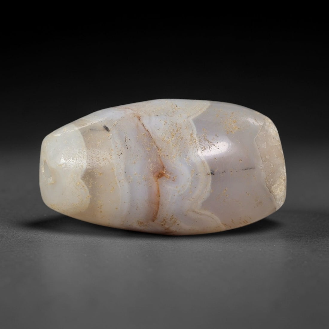 Ancient Banded Agate Bead - Silk Road Indus Valley Barrel Bead, 15BC: Carved from banded agate, the bead is fashioned in a compact barrel form, with a central drilled perforation for suspension. The stone exhibits delicate, wavy natural banding in milky white, soft beig