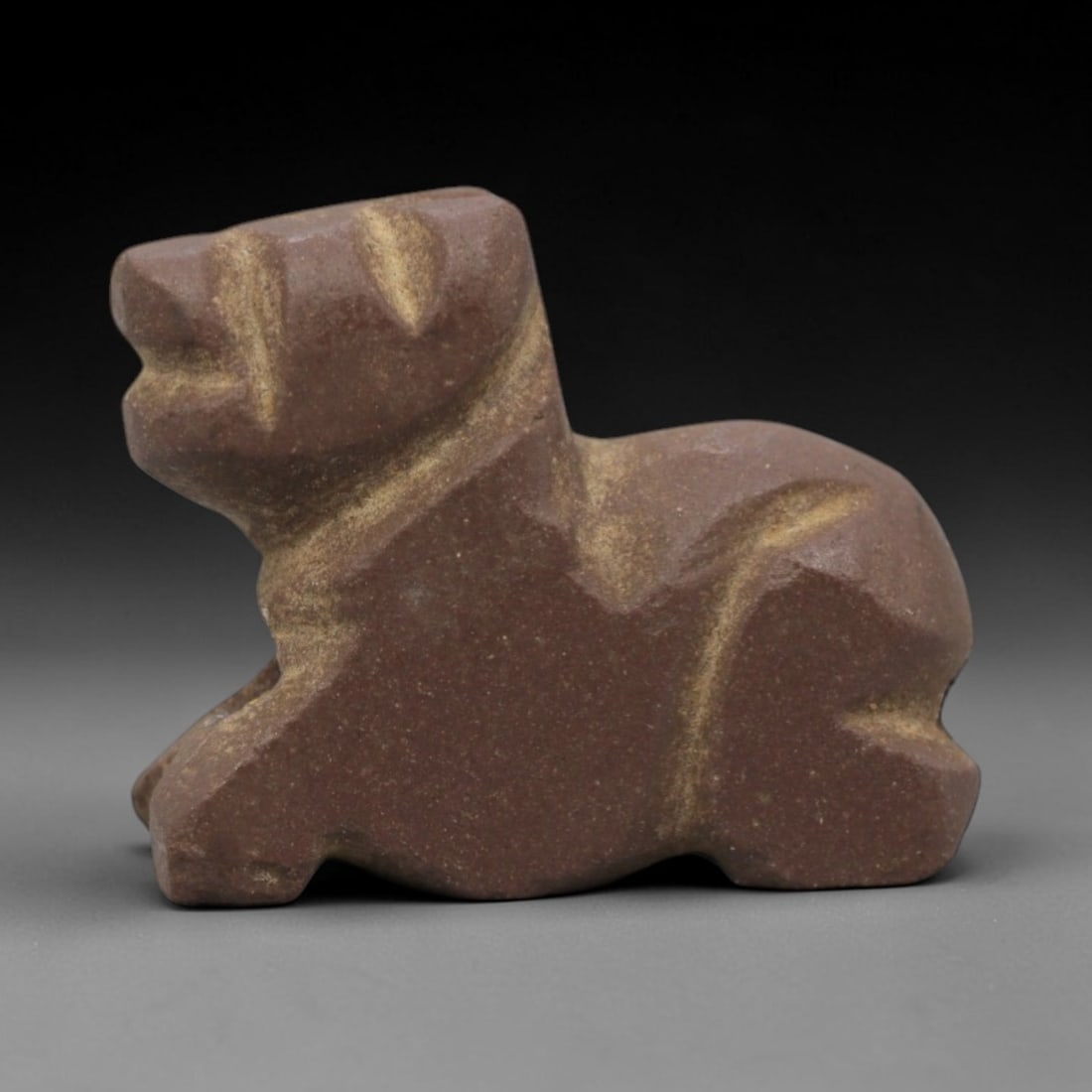 Ancient Near Eastern Stone Feline Amulet - Carved Figurine, 5ZV: This amulet is carved from a dense, reddish-brown stone, likely siltstone or a similar sedimentary rock, with subtle incised details defining its recumbent feline form. The piece depicts a cat in a re