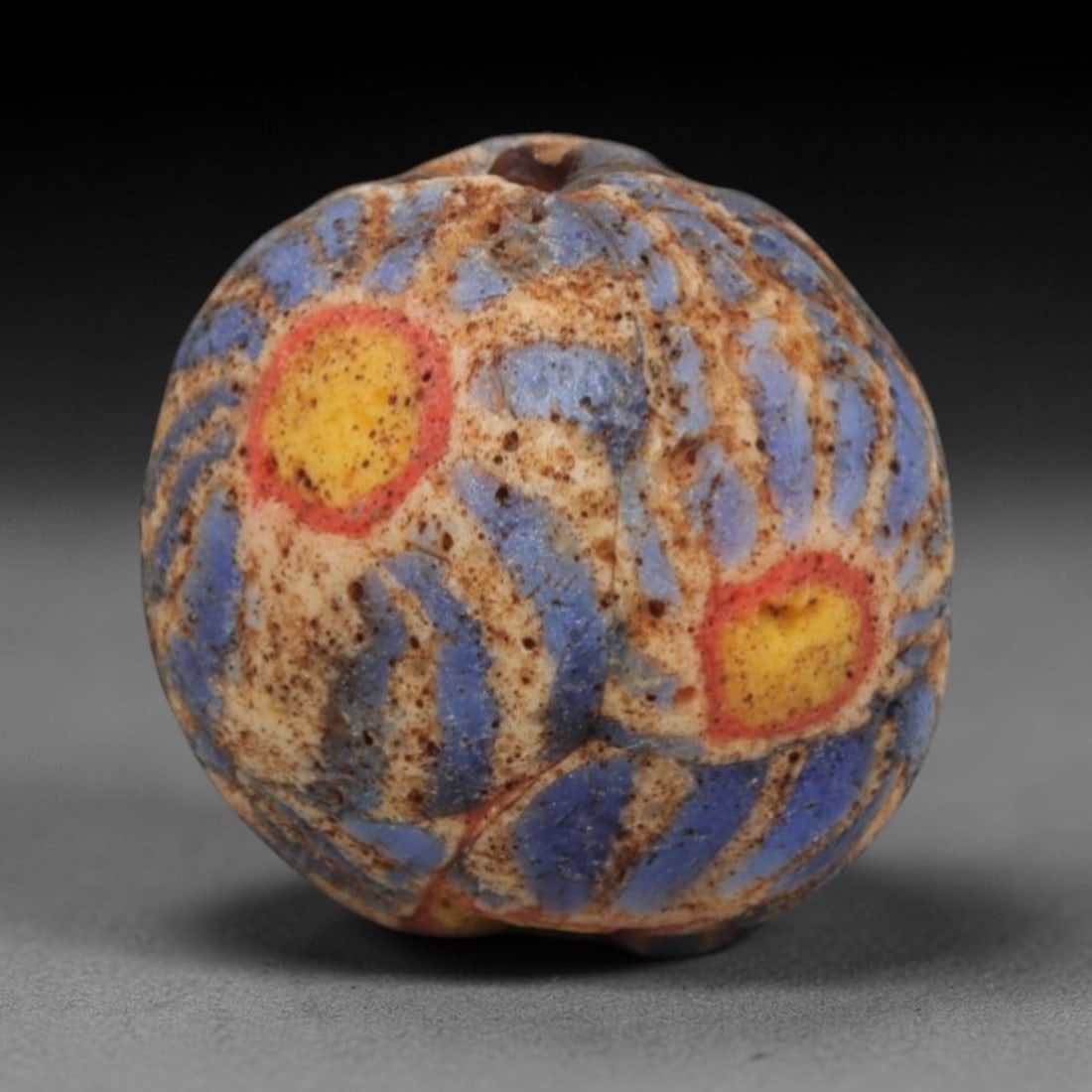 Ancient Glass Bead - Roman Egyptian Eye Motif Amulet, 64ZN: Crafted from mosaic glass, this spherical bead features a central suspension hole and is decorated with striking eye motifs-each consisting of a yellow core encircled by a red ring-set against a backd