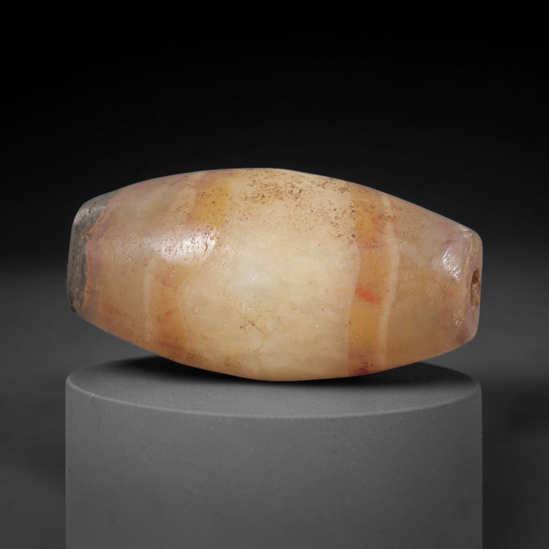 Ancient Agate Bead - Indus Valley Silk Road, 88AS: Carved from banded agate, the bead is fashioned in a bi-conical barrel form with a central perforation for suspension. The stone displays natural concentric banding in creamy beige, soft reddish-orang