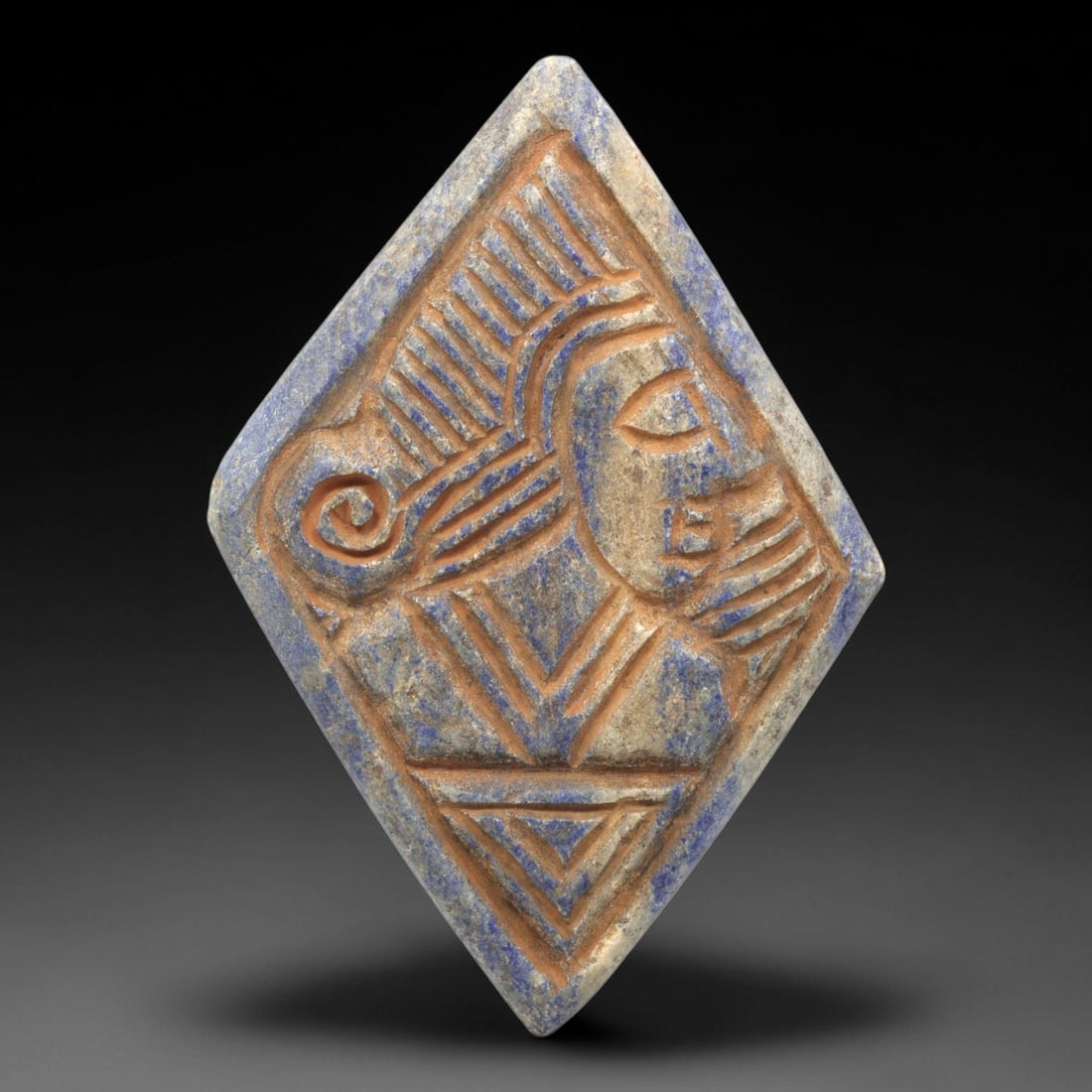 Near Eastern Lapis Lazuli Plaque - Tribal Figure Profile Relief, 13ZA: Carved from rich lapis lazuli, this diamond-shaped plaque features a **7x4.8cm (2.76x1.89in)** relief composition centered on a finely stylized tribal figure in profile, showcasing the iconic linear a