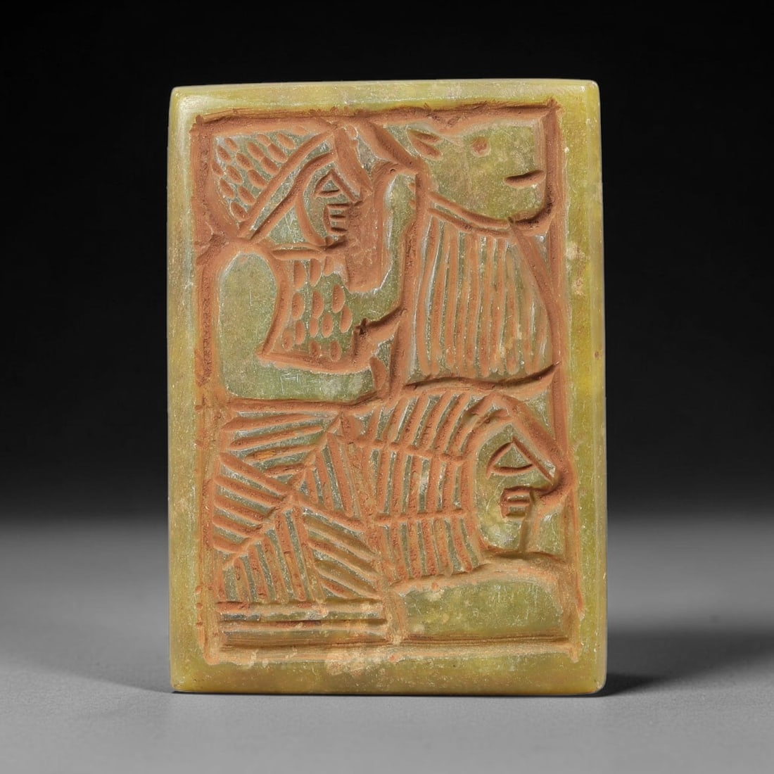 Near Eastern Serpentine Plaque - Tribal Art Figure & Animal Relief, 46BF: Carved from serpentine, this rectangular plaque presents a deeply incised relief composition featuring a stylized human figure alongside two distinct animal forms, rendered in a bold, linear tribal ae