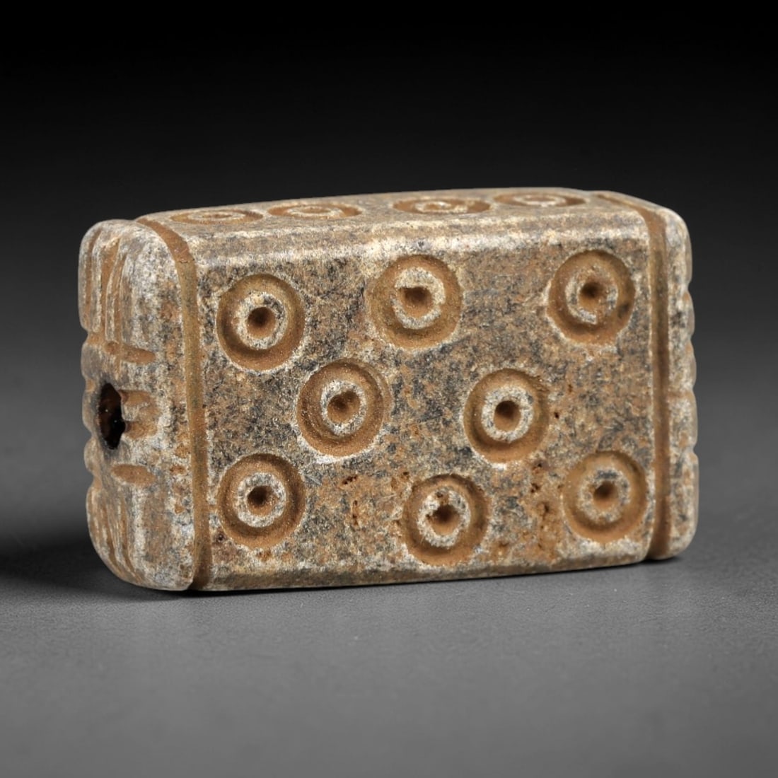 Ancient Steatite Amulet - Near Eastern Concentric Circles, 36AK: Crafted from steatite, this rectangular prism amulet features deeply incised concentric circle motifs arranged in a 3x3 grid across its primary face, with subtle linear carvings along the lateral edge