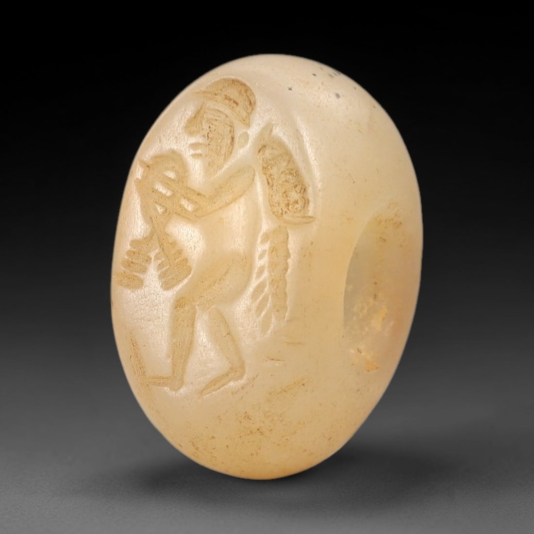 Ancient Chalcedony Hemispherical Stamp Seal - Near Eastern Male Figure Amulet, 10AN: This ancient Near Eastern hemispherical stamp seal is carved from translucent, pale creamy chalcedony, with a smooth, polished surface and subtle earthy patina. The seal's oval face depicts a striding