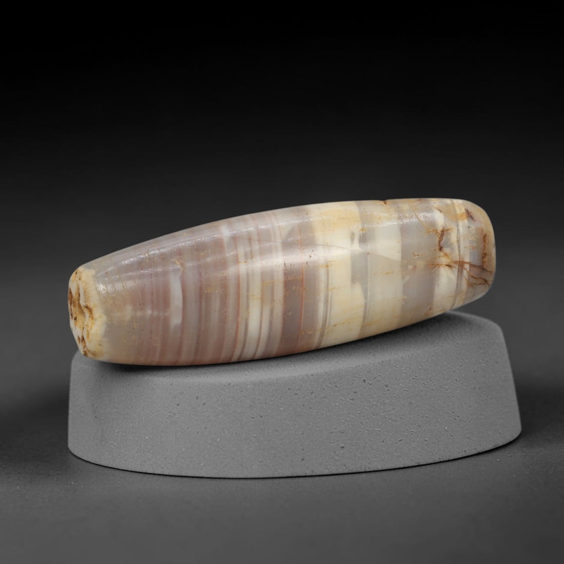 Ancient Agate Bead - Indus Valley Banded Carving, 78WJ: This artifact is crafted from banded agate, exhibiting distinct, parallel banding in muted lilac-grey, creamy white, and pale amber hues across its polished, elongated surface. The bead is shaped in a