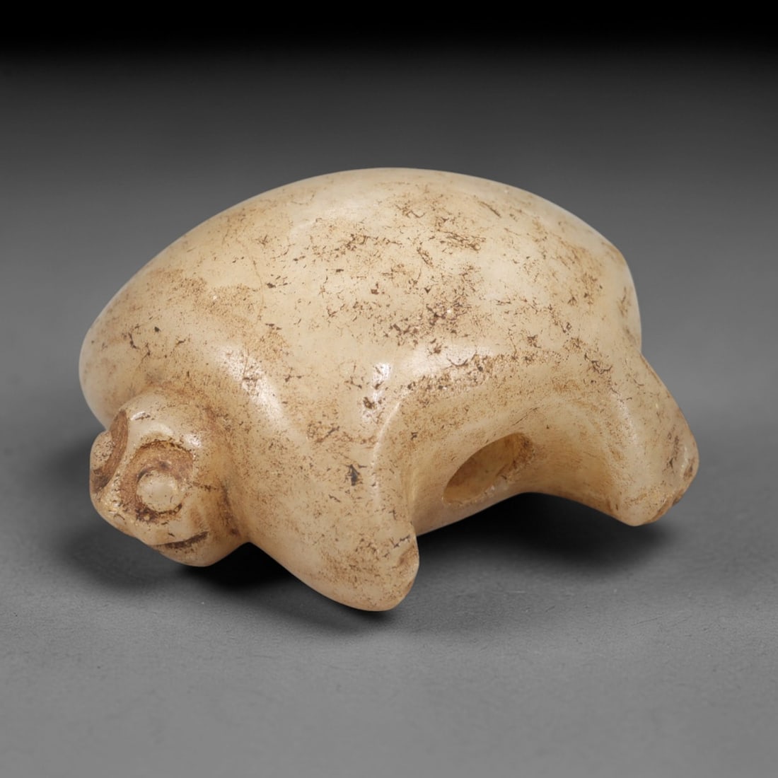 Ancient Stone Tortoise - Near Eastern Amulet Figurine, 1AL: Carved from smooth, pale stone, this amulet depicts a stylized tortoise with a rounded shell, simplified facial features, and short limbs, with a lateral suspension hole for wearable use. Attributed t